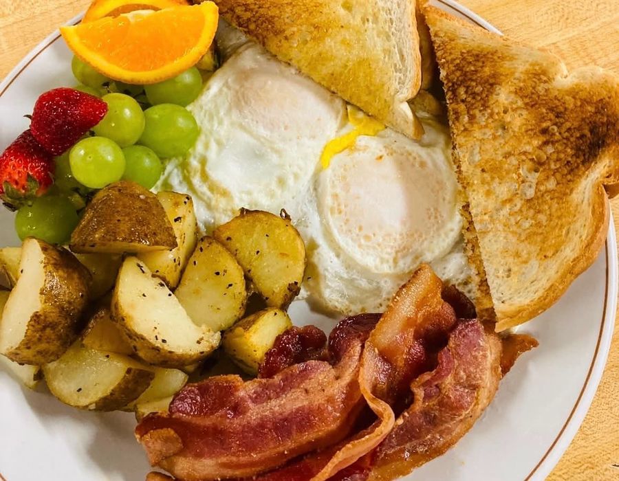 Plate of eggs, bacon, toast and fruit
