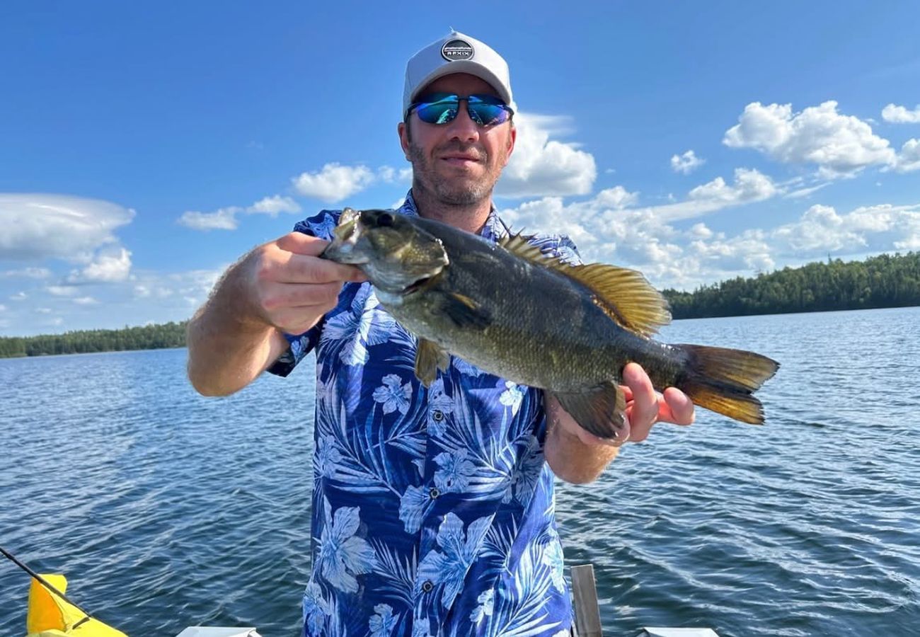 Angler holding a smallmouth bass under a blue sky