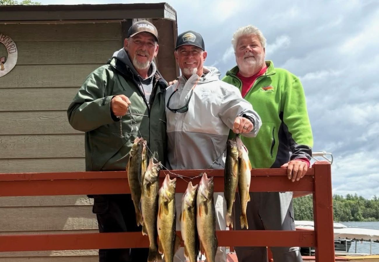 Three anglers on the deck with a stringer of walleye